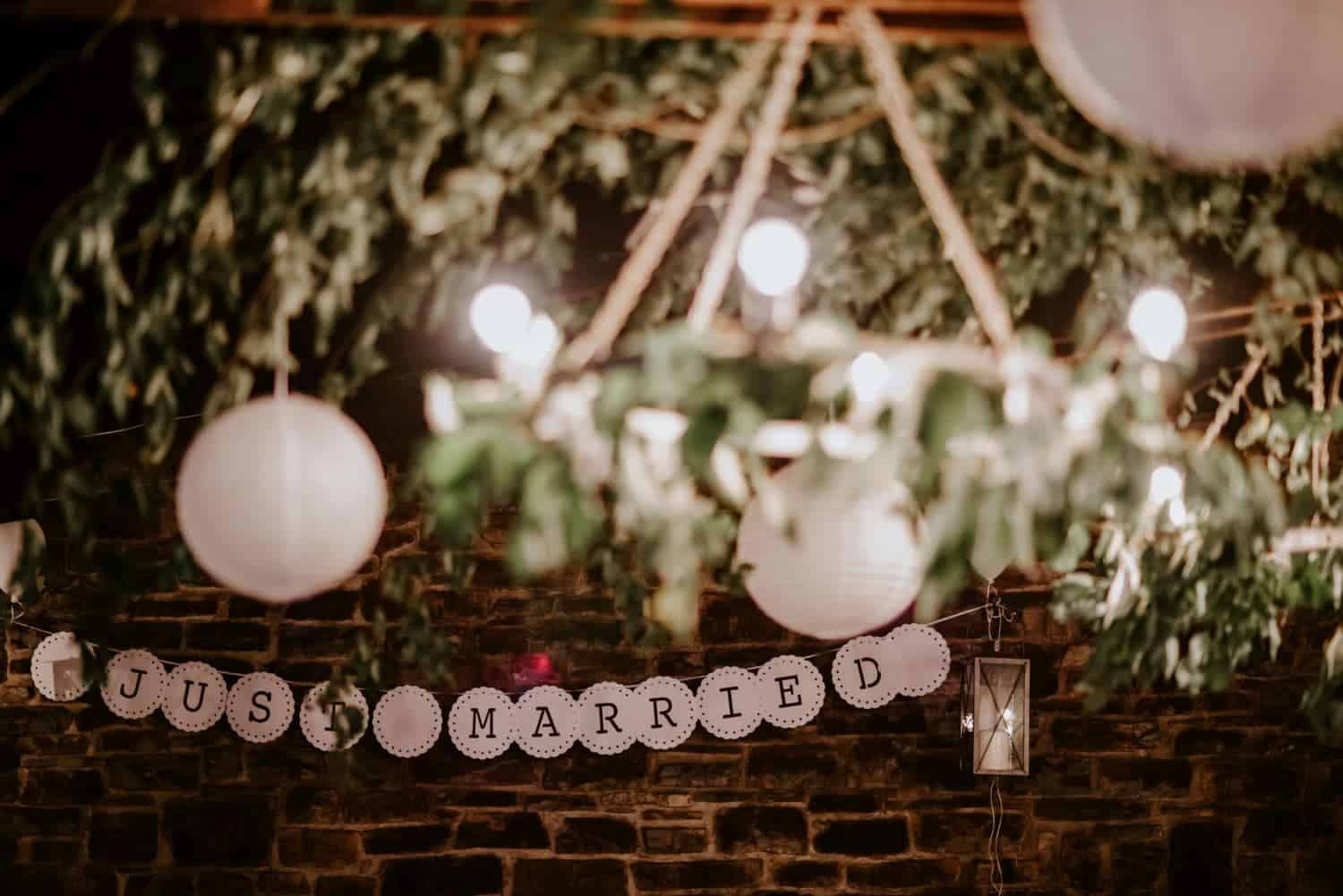 a sign from a string with lights and a brick wall
