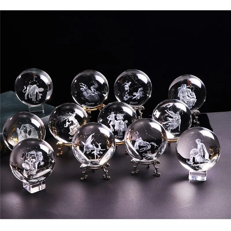 Scorpio Season 4 Twelve crystal balls, each engraved with a different zodiac sign and corresponding figure, are displayed on small stands in two rows against a dark background.