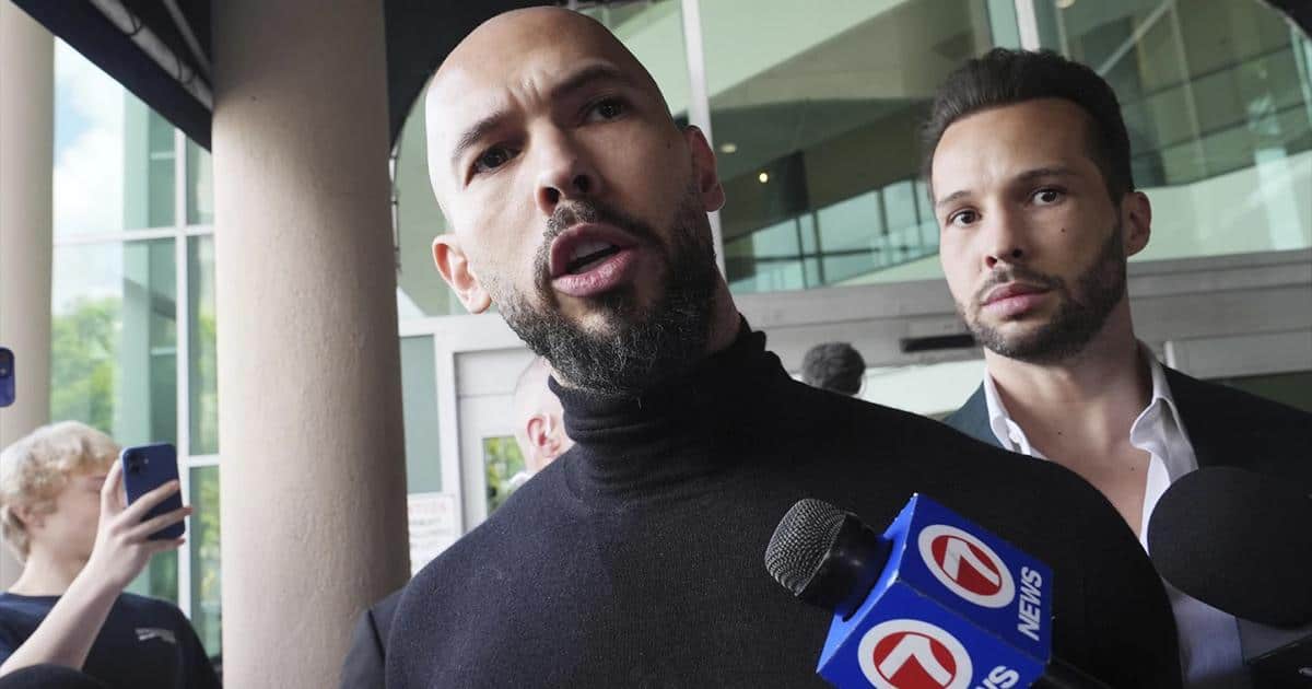Andrew Tate speaks to reporters outside a building, holding a microphone with a "7 News" logo. Tristan Tate stands behind him, looking on. The **Tate brothers** are likely facing **criminal charges** related to the **UK investigation**.