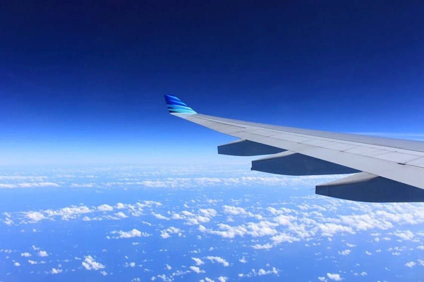 Wing of aircraft in blue sky above the clouds / Tips For Your First Long-Haul Flight