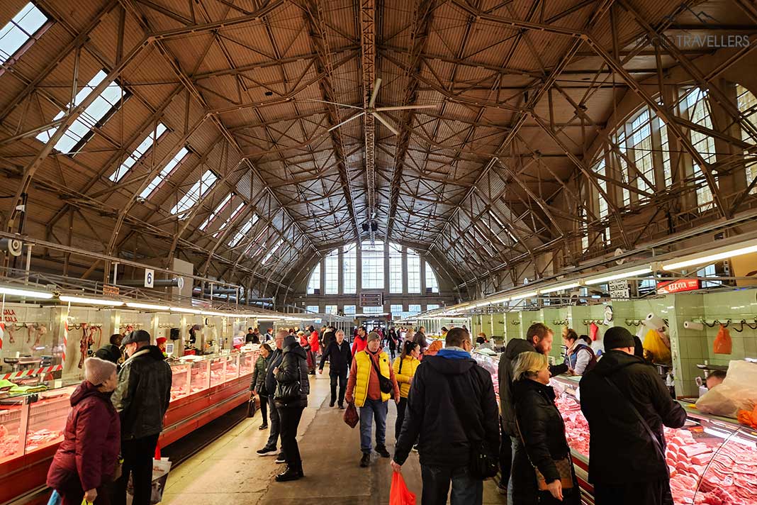 Menschen stehen vor den Regalen in der Markthalle von Riga