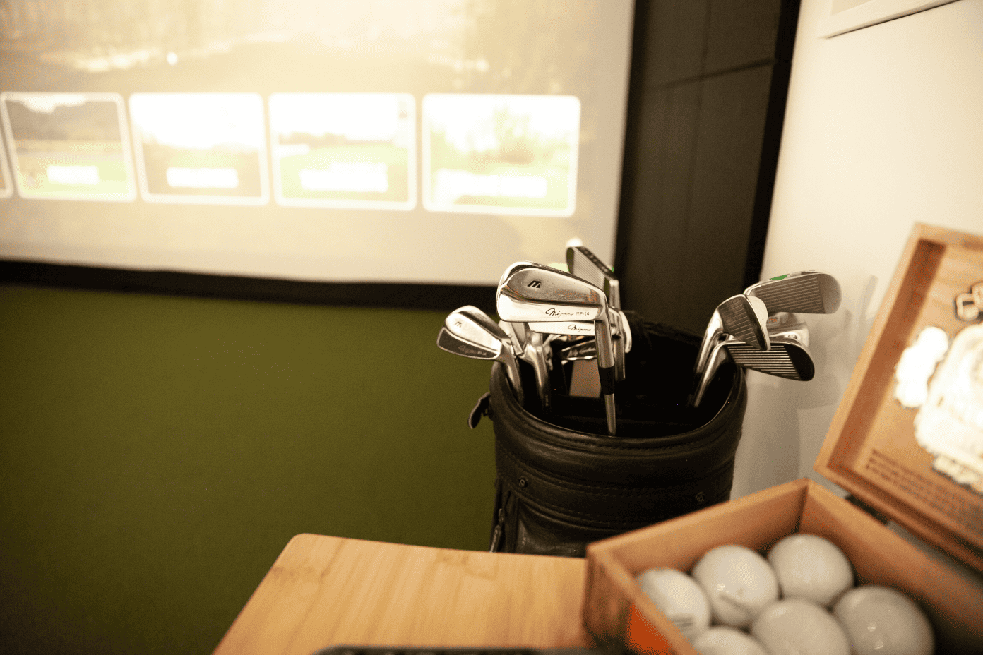 Indoor golf simulator with golf clubs and balls.