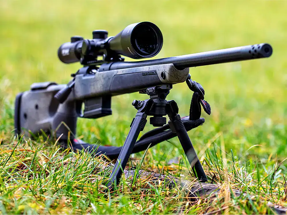 Präzises Jagdgewehr-Setup mit Zweibein und Zielfernrohr Präzises Jagdgewehr mit Zielfernrohr auf Zweibein im Gras für ein stabiles Schuss-Setup