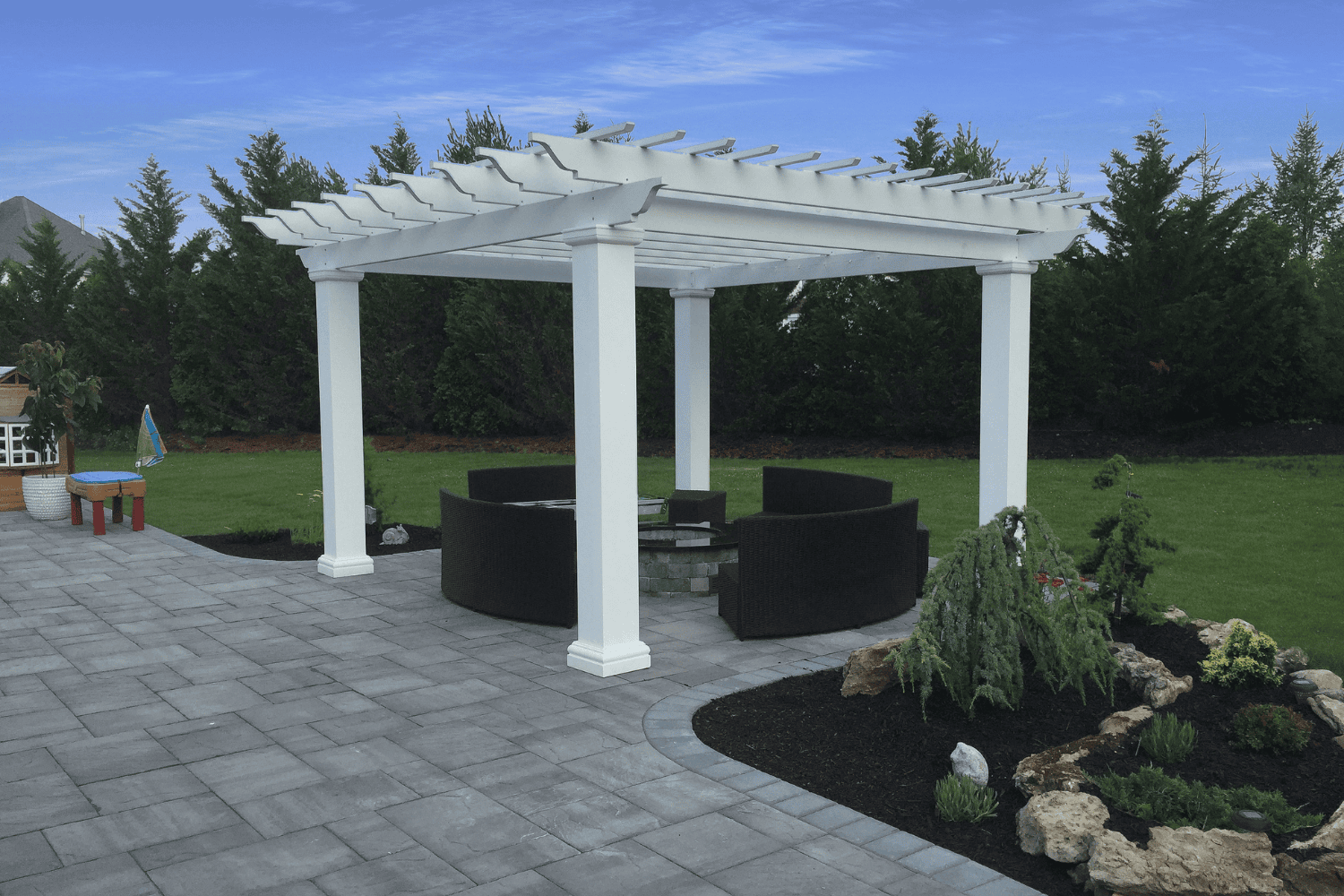 A white pergola creates a cozy retreat, featuring a fire pit and a bench—perfect for relaxing evenings. Explore more stunning pergolas and pavilions to elevate your outdoor living space.