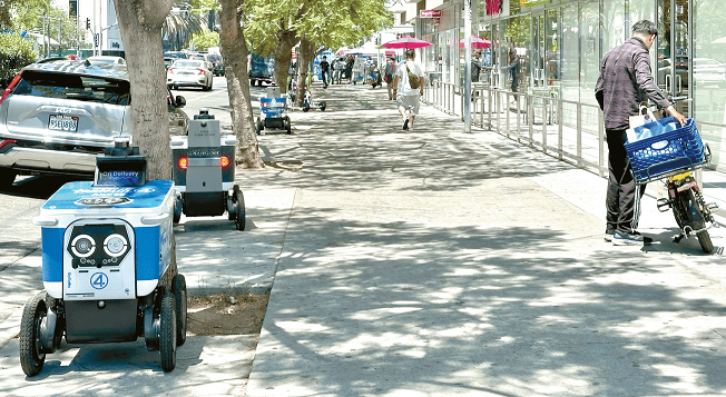 delivery robots in Los Angeles lined up outside restaurant while delivery driver prepares to leave on Wilshire Boulevard