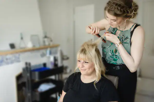 Absolventin der Famous Face Academy Luisa Niederhauser stylt die Haare einer blonden Frau