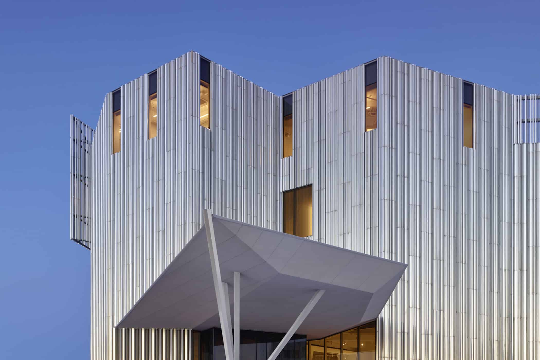 Close-up of the Oklahoma Contemporary Arts Center entrance, showcasing the aluminum fin façade and cantilevered canopy at twilight.