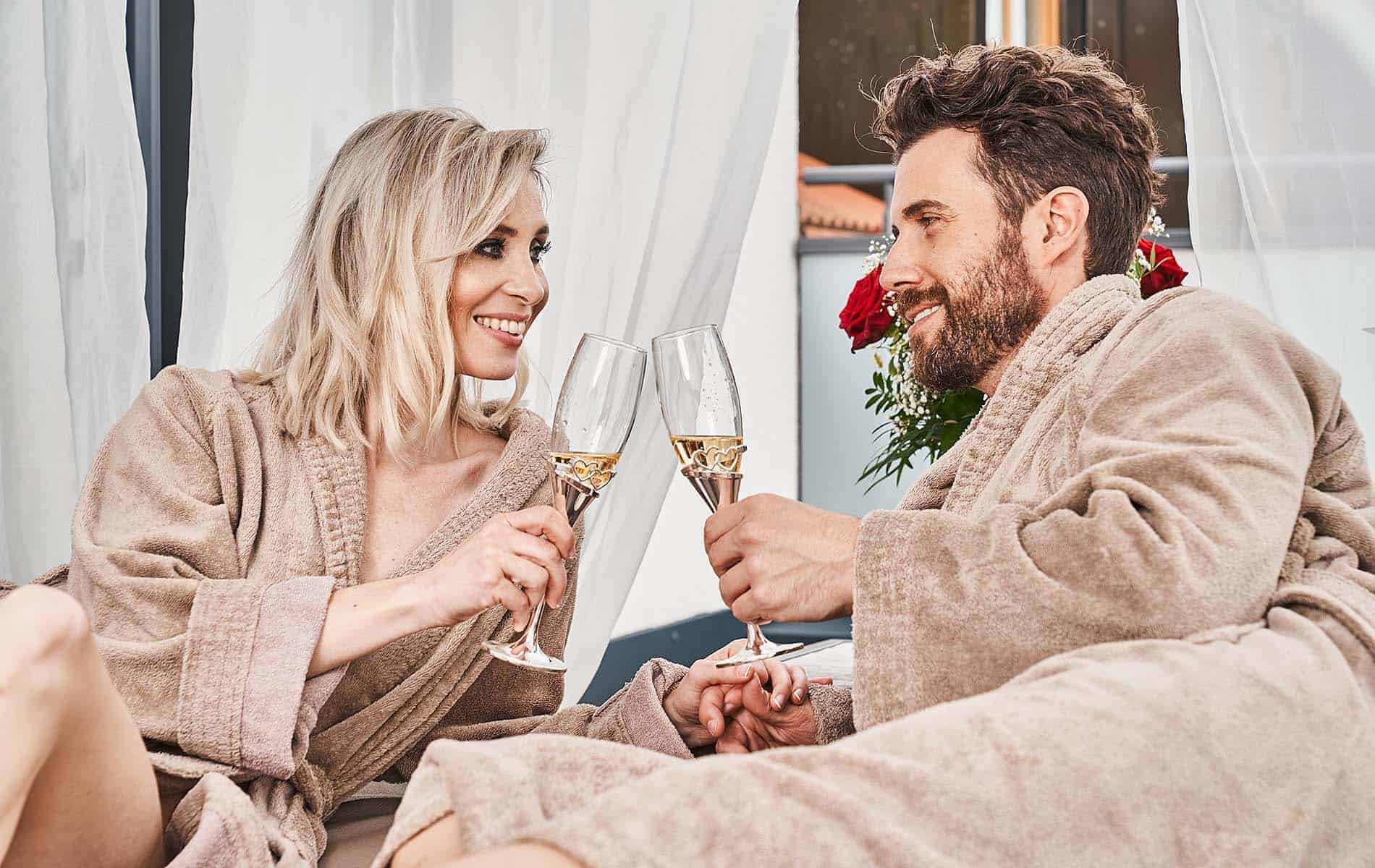 Paar trink Sekt im Bademantel in der Wellnesssuite