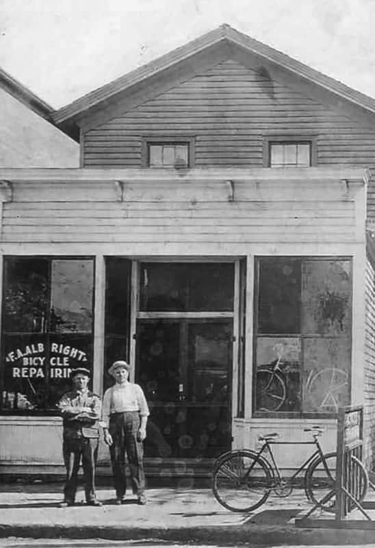 Albright's Bicycle Faded black and white photo of a historic building with bicycles and two boys standing outside, early 20th century scene, The History Museum.