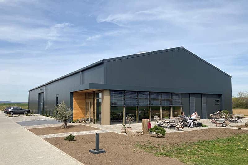 Betriebshalle Weingut von ELF Große Hallenlösung für Weingut von ELF, graue Halle mit Terrasse und Sitzmöglichkeiten
