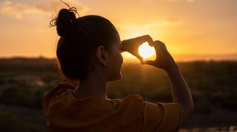 Woman making heart sign with hands.