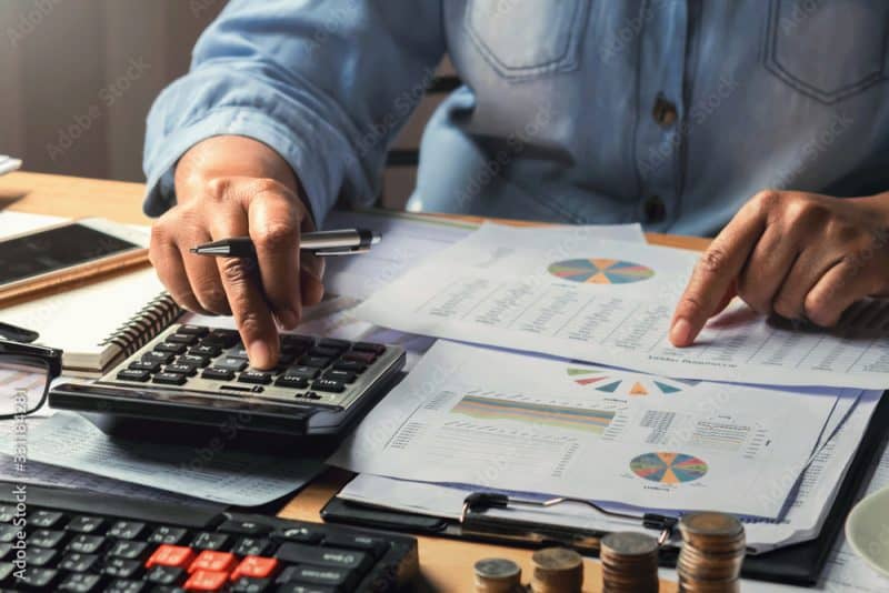 a woman working using calculator with money stack in office