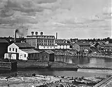 mill A historic black and white photo of The History Museum with surrounding industrial buildings in the background.