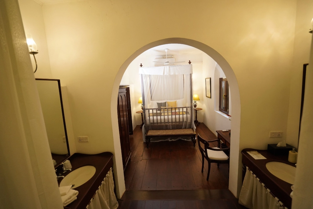 Perspective from an archway into the bathroom of the Lime Butterfly room at Adigar's Manor, highlighting its decor.